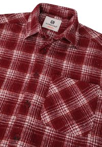 Camisa de franela a cuadros rojos con cuello puntiagudo, cinco botones, bolsillo en el pecho y tejido texturizado con acentos en blanco.