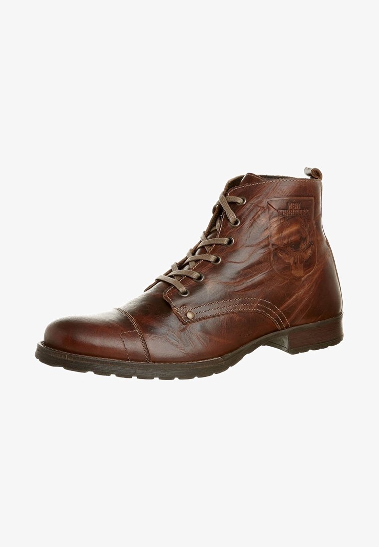 Stivaletti alla caviglia in pelle marrone con punta arrotondata, design con lacci e un sottile emblema a forma di teschio sul lato. Superficie testurizzata con cuciture visibili.