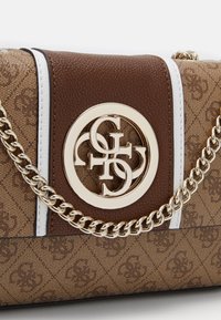 Brun mønstret håndtaske med guldfarvet hardware, med en cirkulær logo og kæderem. Designet inkluderer hvide og brune accenter.