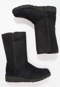 Czarne zamszowe kozaki do połowy łydki z płaską, teksturowaną podeszwą, przeszyciami i detalem w postaci przedniego przeszycia. Gładkie wykończenie z zaokrąglonym czubkiem.