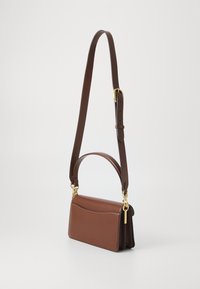 Brown leather shoulder bag with a flat design, adjustable strap, gold hardware accents, and a pocket detail on the front.