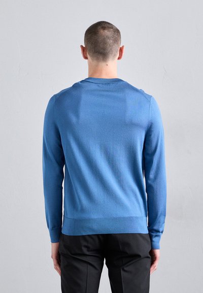 Mėlynas megztinis su ilgomis rankovėmis, apvaliu kaklu, raišteliais ant rankogalių ir apatinės dalies. Lygus paviršius su prigludusia siluetu. Paprastas dizainas.