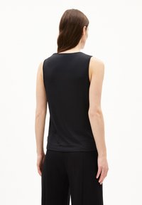 Top nero senza maniche realizzato in un tessuto morbido e liscio. Presenta un design semplice con scollatura arrotondata e un'etichetta logo discreta sul lato inferiore.