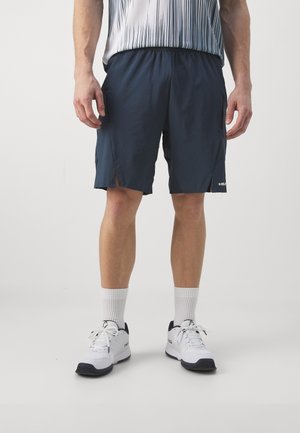 Heren navy shorts met zijzakken, lichtgewicht materiaal, elastische tailleband en uitsnijdingen. Gecombineerd met witte sportschoenen en sokken.