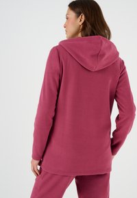 Felpa con cappuccio in rosa intenso, caratterizzata da un cappuccio, maniche lunghe e una vestibilità rilassata. Texture morbida con una finitura liscia e cuciture minime.