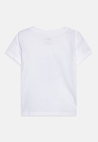 Camiseta de algodón blanca con cuello redondo y mangas cortas. Presenta una pequeña etiqueta impresa en la parte posterior con detalles de la marca e instrucciones de cuidado.