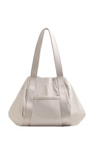 Beige tygväska med två långa remmar, en avslappnad form och en liten ytterficka. Slät textur och minimalistisk design.