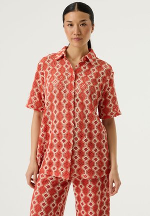 Rood overhemd met patroon, korte mouwen, een kraag en een halfdoorzichtige stof met geometrische ontwerpen in wit en beige.