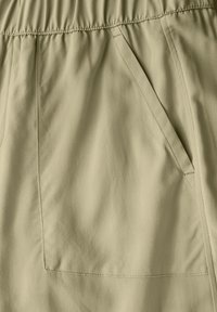 Licht kaki shorts met een elastische tailleband, voorzien van zijzakken en een soepele stofstructuur. Eenvoudig ontwerp met nauwkeurige stikseldetails.