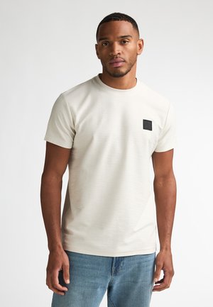 Lichtbeige T-shirt met ronde hals gemaakt van gestructureerde stof, met een zwart vierkant logo patch op de linkerbuste, korte mouwen en een normale pasvorm.