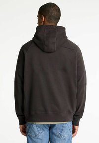 Sudadera gris oscuro de corte holgado, con una capucha grande, puños acanalados y dobladillo. La tela parece suave, con costuras mínimas visibles.