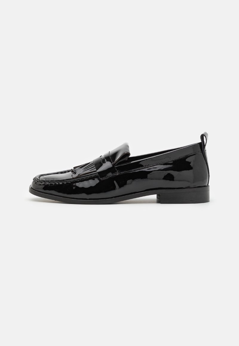 Mocassins en cuir verni noir avec un nœud décoratif et un pompon, dotés d'un petit talon et de détails cousus le long de la tige.