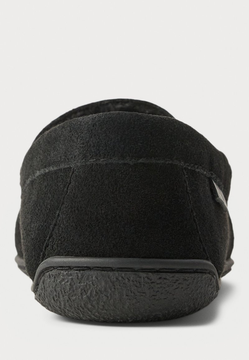 Schwarze Wildlederschlüpfschuhe mit einer strukturierten Gummisohle und dezenten Steppdetails entlang der rückseitigen Naht und dem oberen Rand.