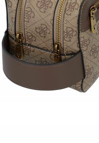 Bruine handtas met patroon en gouden hardware, twee ritsen en een effen bruine schouderband. Kenmerkt zich door textuurmateriaal en een gestructureerd ontwerp.