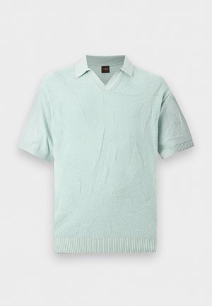 Polo bleu clair à manches courtes avec motif abstrait texturé, poignets et ourlet côtelés, et petit col plié.