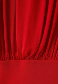 Material roșu cu suprafață texturată, cu pliuri în zona taliei și tiv neted. Materialul pare moale și elastic.