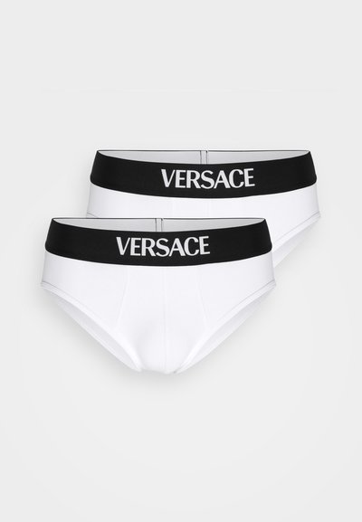 Fehér pamut alsónadrág fekete elasztikus derékpánttal, amelyen fehér "VERSACE" logó található. Két pár látható, klasszikus alsónadrág dizájn.