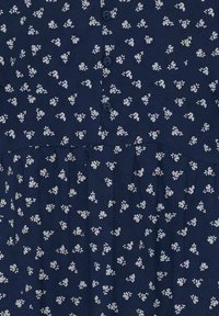 Tissu bleu marine avec un petit motif floral blanc et trois boutons bleus au centre.
