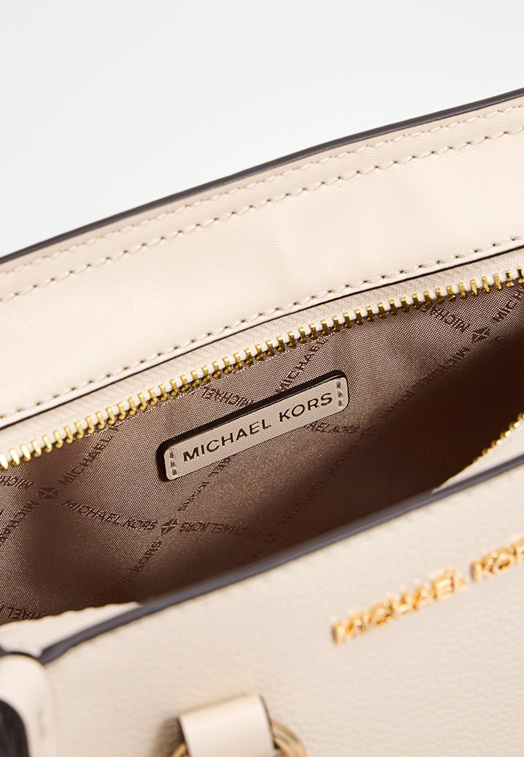Beige Handtasche von Michael Kors mit offenzipper in Gold, die das Innenfutter und das eingestickte Markenlogo zeigt.