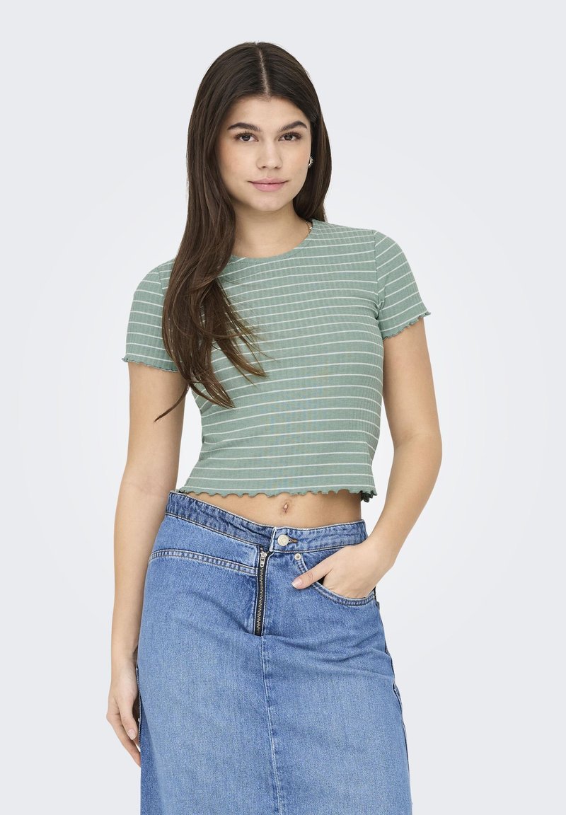 T-shirt cropped rayé vert avec des bords festonnés, associé à une jupe en denim taille haute avec une fermeture éclair à l'avant et une poche.