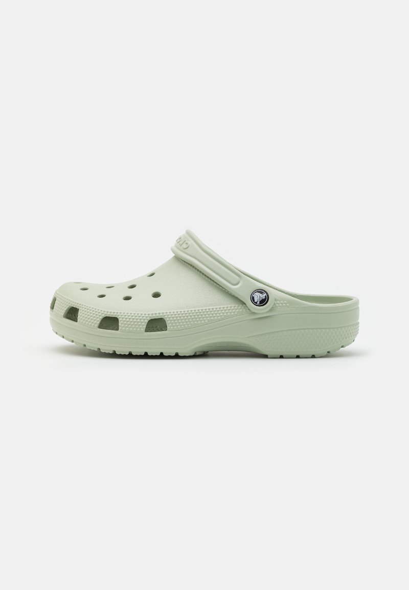 Sabot vert clair à enfiler avec des trous de ventilation, semelle texturée et bride de talon réglable avec un badge rond à logo.