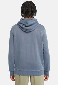 Sudadera con capucha azul de tejido suave, con capucha ajustable con cordón, puños y bajo acanalados. Incluye un bolsillo canguro y un corte relajado.