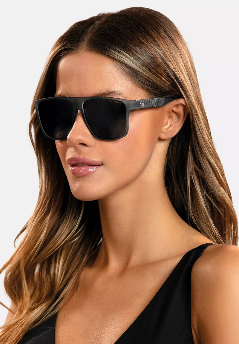 Okulary przeciwsłoneczne z czarnymi ramkami z poliwęglanu i ciemnymi soczewkami, charakteryzujące się prostokątnym kształtem i teksturowanymi detalami na zausznikach.