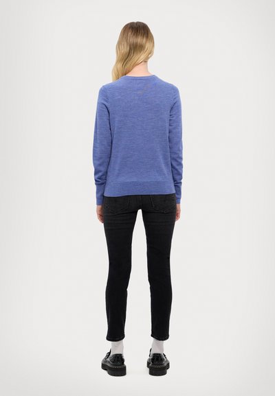 Blå långärmad tröja med mjuk textur och rundad hals, i kombination med svarta skinny jeans och stubbar svarta skor. Enkelt och minimalistiskt design.
