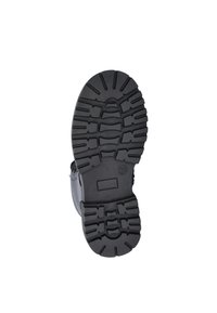 Zwarte rubberen laarszool met diepe profielen en groeven voor grip. Heeft een gladde omtrek en een lichte kromming bij de hak voor comfort.