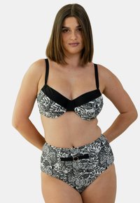 Bikini à imprimé floral noir et blanc avec un haut de bikini à armatures et un bas taille haute ; présente des accents noirs et des garnitures décoratives.