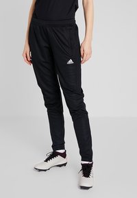 Schwarze Sporthose aus leichtem Material mit elastischem Bund, seitlichen Taschen und einem weißen Adidas-Logo auf der linken Hüfte.