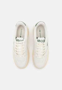 Sneaker bianche in pelle con accenti verdi, design perforato, lacci piatti e suola in gomma. Branding visibile sulla linguetta e sulla soletta.