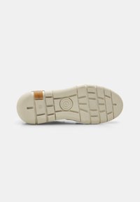 Suola di scarpa in gomma con un motivo testurizzato, caratterizzata da profonde scanalature per una migliore aderenza. Il colore è beige chiaro con un piccolo accento marrone vicino al tallone.