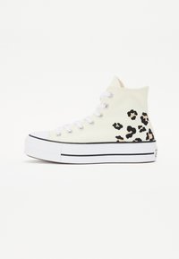 Höga sneakers med en crèmefärgad duköverdel, svart och beige leopardmönster, vita snören och en tjock vit sula med svarta ränder.