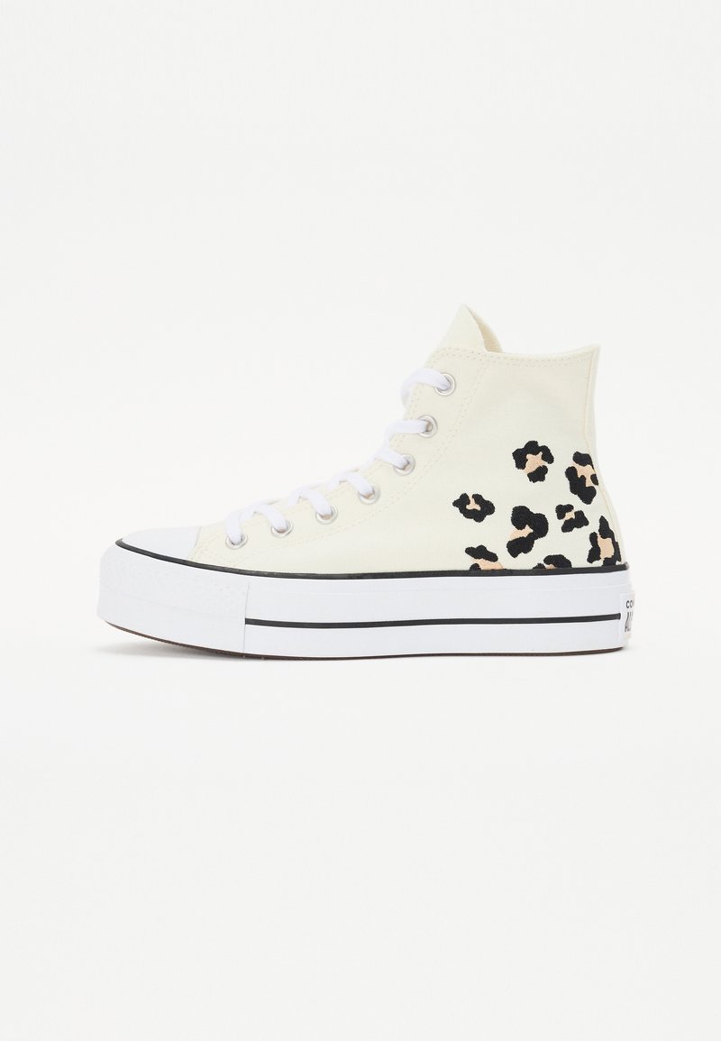 Höga sneakers med en crèmefärgad duköverdel, svart och beige leopardmönster, vita snören och en tjock vit sula med svarta ränder.