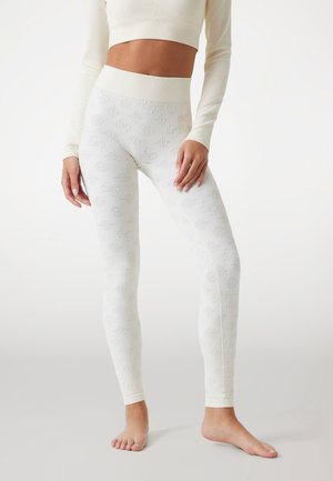 White leggings with a textured pattern featuring floral and circular designs. High waistband and stretchy fabric for comfort and fit.