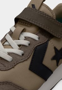 Μπέζ και καφέ αθλητικό παπούτσι με λευκά κορδόνια, σκούρο καφέ λουρί και μαύρο αστέρι και λογότυπο chevron στο πλάι.