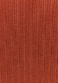 Textil mit strukturierter Oberfläche in warmem Rotton, das vertikale gerippte Streifen aufweist. Das Muster ist gleichmäßig und gleichmäßig über die Fläche verteilt.