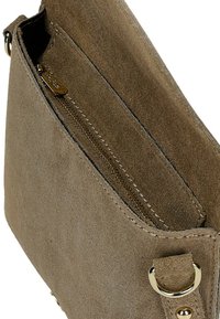 Bruine suède crossbodytas met gouden ritssluiting en metalen ringbeslag, met een open bovenkant en een binnenvak.