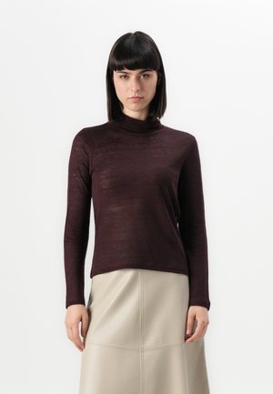 Burgundi turtleneck-sviiter, mis on valmistatud peenes, veidi läbipaistvas kudumisest. Formaalselt istuv siluett pikkade varrukatega, koos beeži seelikuga.