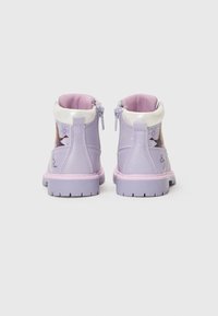 Bottines synthétiques violettes avec une finition brillante, col en fourrure blanche, et graphiques décoratifs ; avec fermeture éclair et semelles texturées.