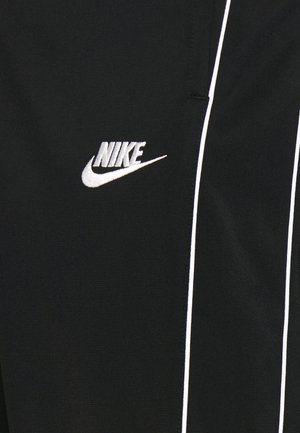 Schwarzer Stoff mit weißem Nike-Logo und Swoosh, mit zwei vertikalen weißen Streifen auf der rechten Seite.