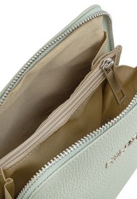 Borsa in pelle texture verde menta con chiusura a zip. L'interno presenta una fodera in tessuto color cammello e una tasca con zip separata per una migliore organizzazione.