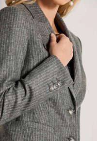 Grijze wollen blazer met een krijtstreep patroon, met notch revers en drie knopen aan de mouw; fijn gestructureerde stof.