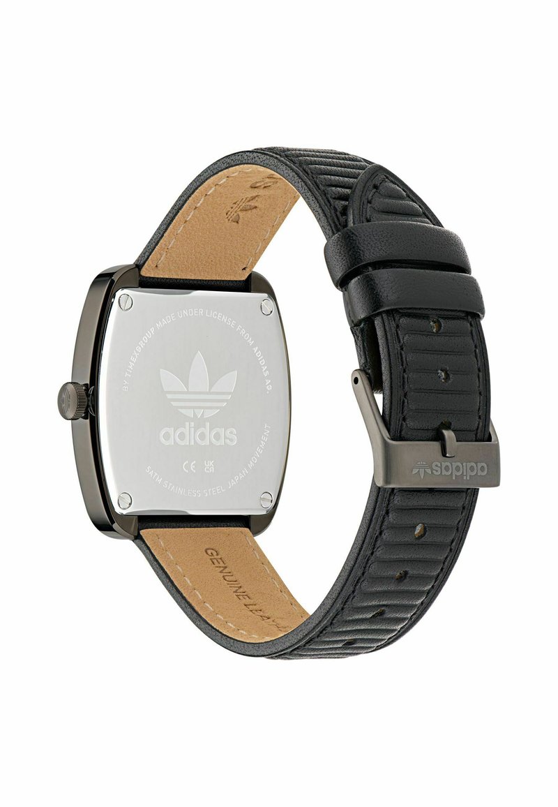 Montre rectangulaire noire avec boîtier en acier inoxydable, bracelet en cuir et accents en relief ; arbore le logo Adidas au dos.