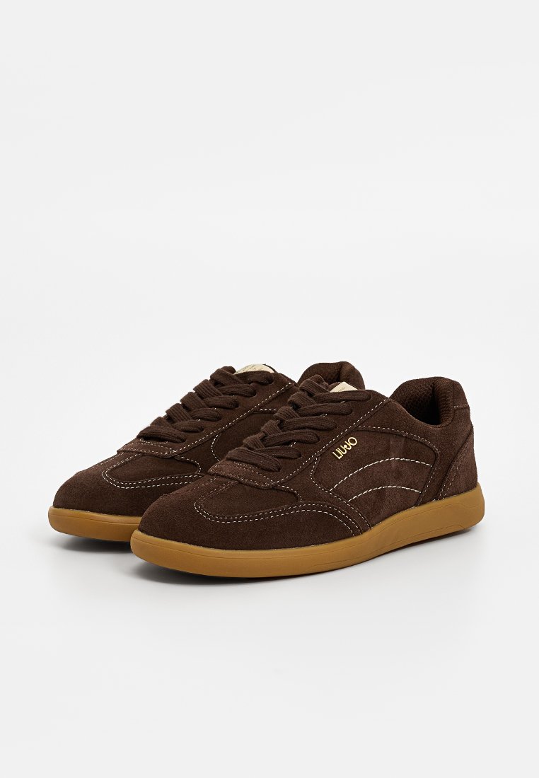 Brązowe zamszowe sneakersy z gumową podeszwą. Posiadają fakturowaną powierzchnię, białe akcenty w postaci przeszyć i logo z boku. Klasyczny design na sznurówki.