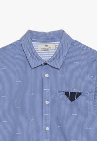 Blauw gestreept overhemd met knoopsluiting, voorzien van een borstzak en witte logopatronen over de stof. Zachte katoenen materiaal.