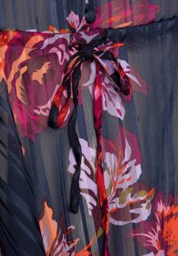 Tissu transparent à motif floral de couleur bleu marine foncé, présentant une fermeture à lien en ruban et des rayures texturées. Les couleurs incluent le rose, l'orange et le violet.