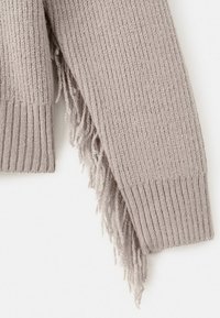 Light grey knitted shawl with ribbed texture and fringed edges, crafted from a soft material for added warmth and comfort.