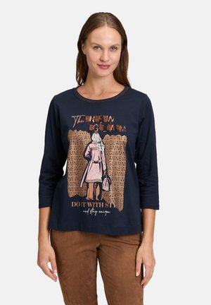 Chemise à manches longues bleu marine en tissu doux, ornée d'un graphisme de personnage en texte rose et doré avec la phrase "Faites-le avec style."